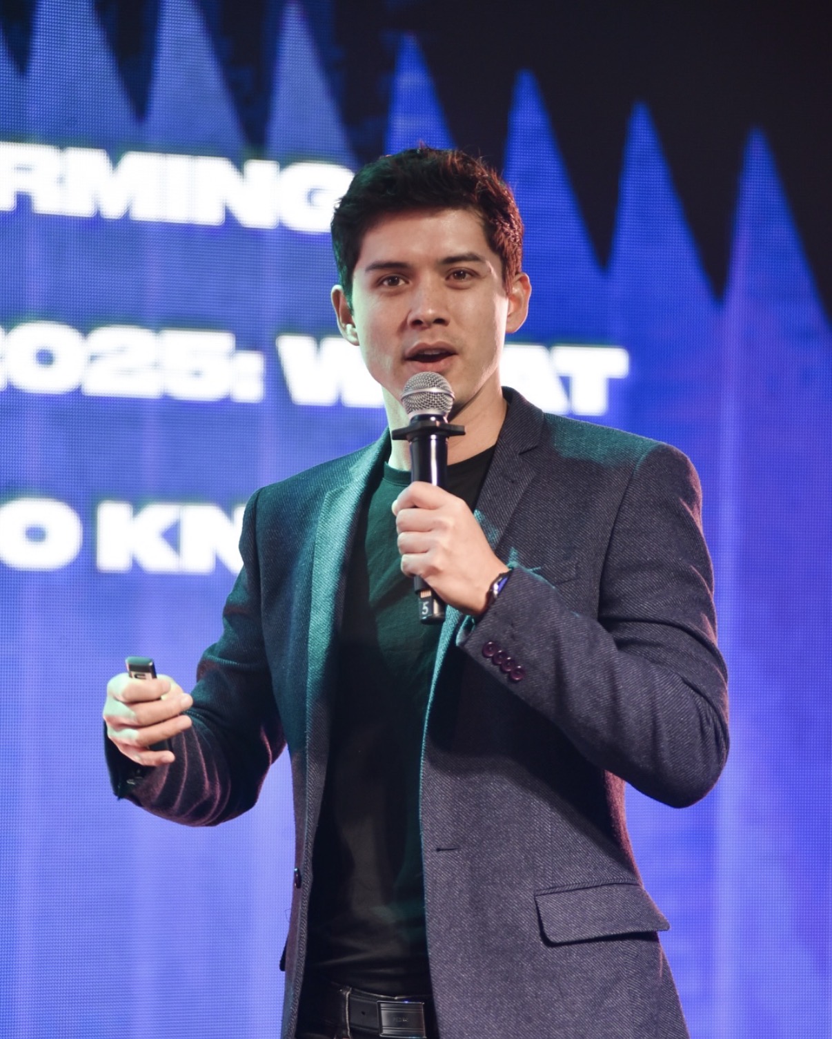 Mike Dee presenting on stage with a microphone